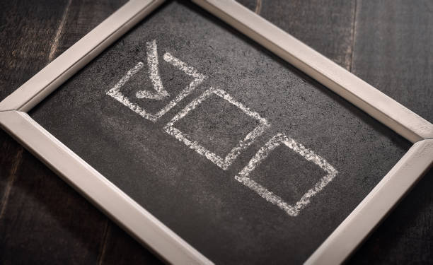istock Blackboard with check boxes on chalk board. Hand writing. Dark background. 1187116048