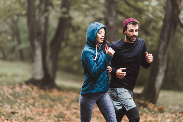 istock Young athletic couple running during cold day in forest. 1187116278