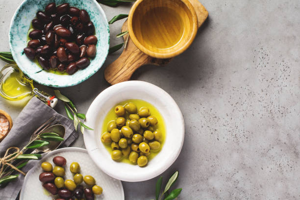 istock Several varieties of fresh olives in different ceramic plates on an old vintage gray table concrete background. Natural product concept. Rustic vintage set of cutlery. Top view, copy space. 1187116357