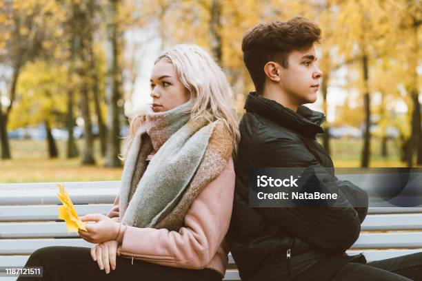Two Teenagers In Love In A Quarrel A Brunette Boy And A Blonde Girl Are Sitting On Opposite Ends Of The Benches Their Backs To Each Other Do Not Want To Talk And Talk Teenage Difficulty Concept Stock Photo - Download Image Now