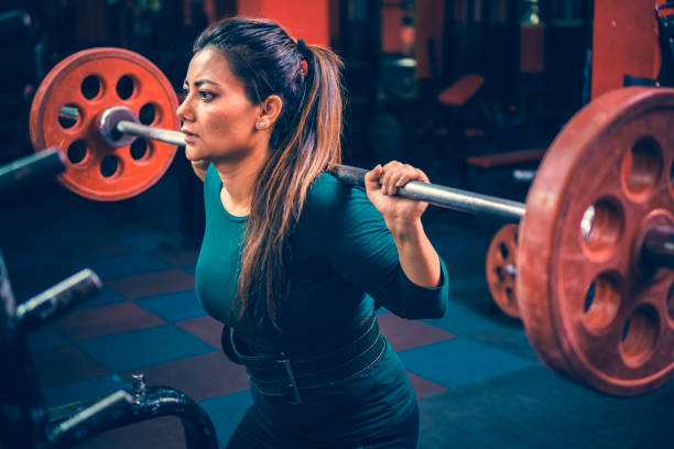 mujer hace sentadillas entrenamiento con una campana en un gimnasio para el fitness. - levantamiento de potencia fotografías e imágenes de stock