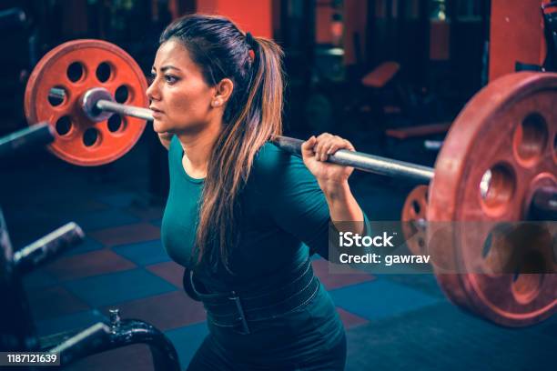 Woman Does Squats Workout With A Barbell In A Gymnasium For Fitness Stock Photo - Download Image Now