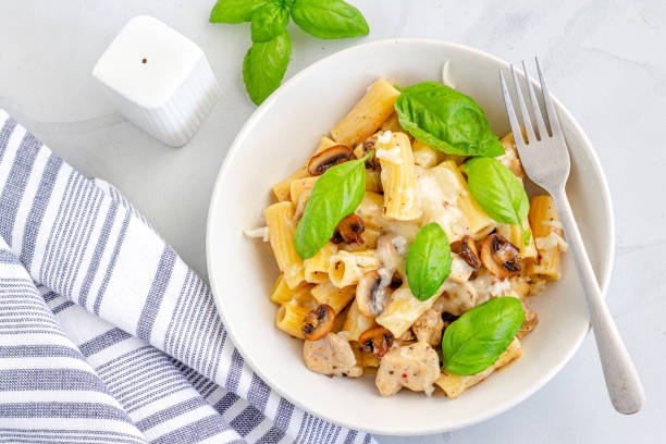 Creamy Mushroom and Chicken Pasta Garnished with Fresh Basil Leaves Creamy Mushroom and Chicken Pasta Garnished with Fresh Basil Leaves Top View, Cooked Rigatoni Pasta Photography. chicken rigatoni stock pictures, royalty-free photos & images