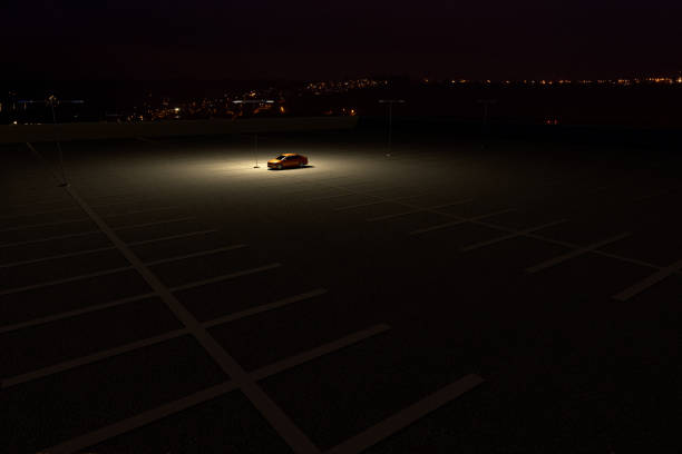 un solo coche en un aparcamiento que representa el concepto de trabajar hasta tarde - conductor asignado fotografías e imágenes de stock