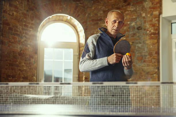 istock Senior man playing table tennis in workplace, having fun 1187124235