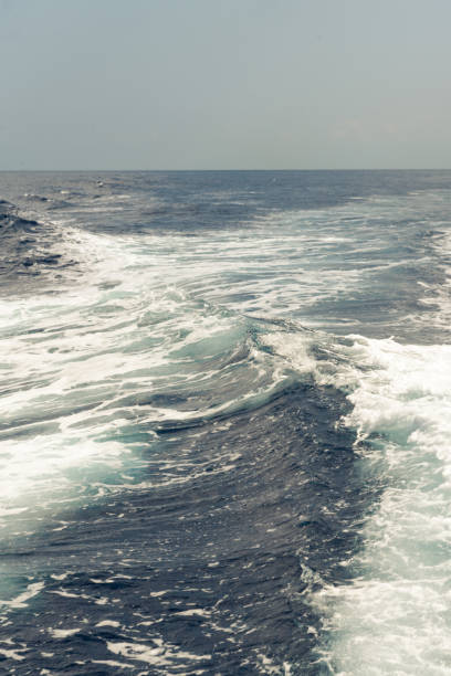 Waves of white foam scatter around. Salt spray sparkles in the sun. Sun glare play on the water. Aegean Sea. Greece.