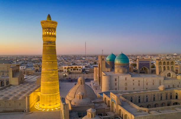 Last daylight at the city of Bukhara, historic silk road, Uzbekistan Panoramic view of the center of Bukhara around the Kalyan minaret (nearly 46 m hight and build in the early 12th century!). In the background of the minaret the Mir-i Arab Madressa and the Kaylan mosque (both 16th century) are visible. The center of Bukhara (also calloed Buchara or Buxoro) is listed as UNESCO World Heritage Site. Bukhara was one of the most important oasis and place of caravanserais at the Great Silk Road. bukhara stock pictures, royalty-free photos & images