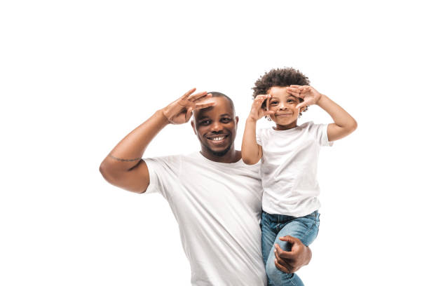 cheerful african american father holding son imitating photo shooting isolated on white cheerful african american father holding son imitating photo shooting isolated on white african father stock pictures, royalty-free photos & images