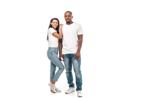 happy african american woman leaning on husbands shoulder while looking at camera on white background