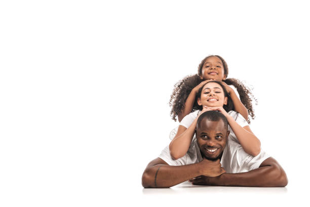 幸せなアフリカ系アメリカ人の女性は、お互いの背中に横たわって、白い背景にカメ�ラで微笑む - offspring child lying on back parent ストックフォトと画像
