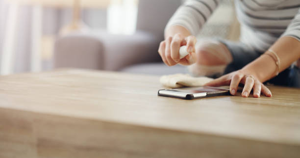 My cellphone needs a good clean Cropped shot of an unrecognizable woman cleaning her device screen at home splash screen stock pictures, royalty-free photos & images