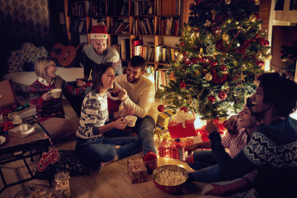 istock Group of friends sitting next to a Christmas tree, and having fun. 1187138025