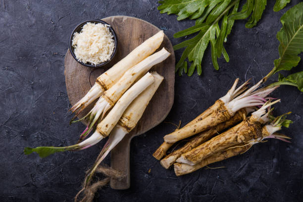 Fresh orgaanic horseradish or Horse-radish root on wooden cutting board.  top view stock photo