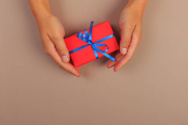 istock gift in female hands on a colored background top view. 1187139741
