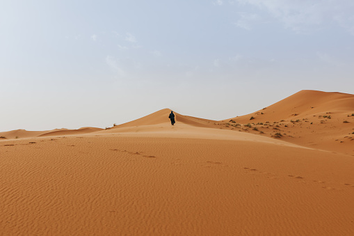 Desert dunes landscape with a berber man walking in the background