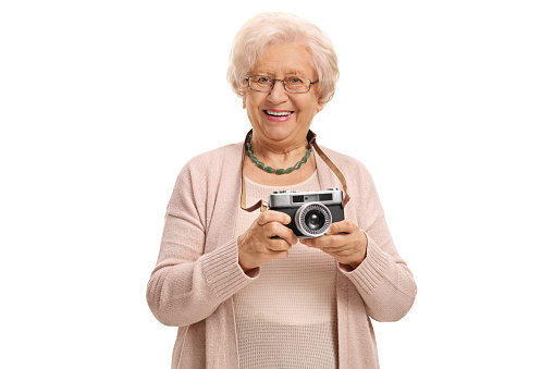 A portrait of an old Polish woman taking a photo with her vintage camera isolated on white