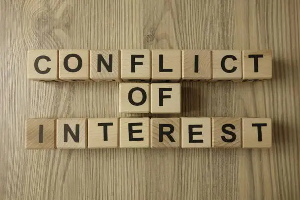 Photo of conflict of interest text from wooden blocks
