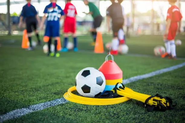 Ladder drills, soccer ball and marker cones on green artificial turf for soccer training equipment.