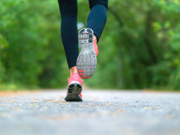 Running woman in the forest. Close-up of sneakers. stock photo
