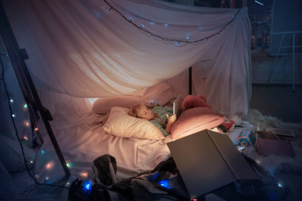 istock Little girl lying in a teepee, playing with the flashlight 1187143533