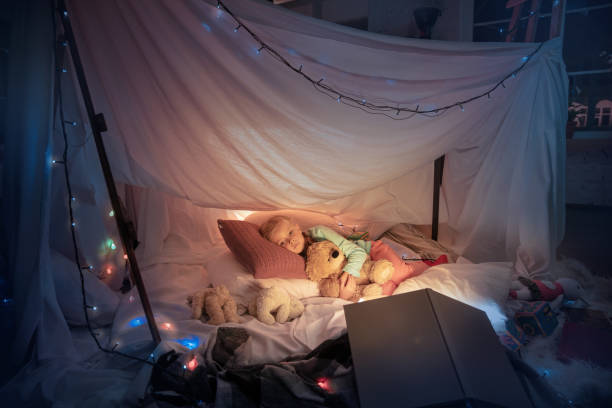 istock Little girl lying in a teepee, sleeping with the flashlight 1187143539