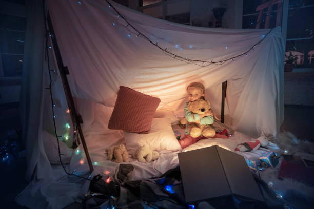 istock Little girl lying in a teepee, playing with the flashlight 1187143546