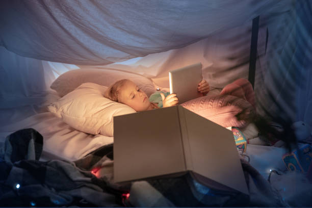 istock Little girl lying in a teepee, playing with the flashlight 1187143561