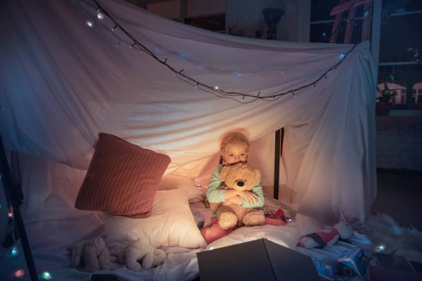istock Little girl lying in a teepee, playing with the flashlight 1187143565