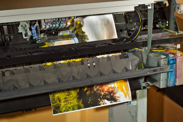 istock Old broken printer in workshop. The concept of cleaning and calibrating printers. Sunset, tent and green grass in the photo. Picturesque nature photo printed on printing equipment. 1187143584