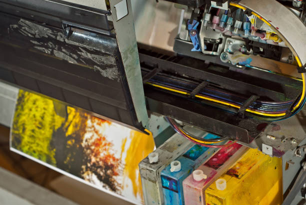 istock Old broken printer in workshop. The concept of cleaning and calibrating printers. Sunset, tent and green grass in the photo. Picturesque nature photo printed on printing equipment. 1187143588
