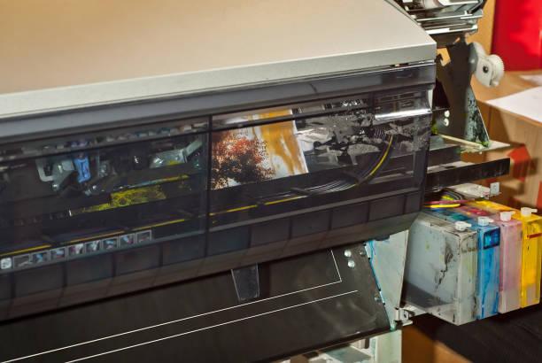 istock Old broken printer in workshop. The concept of cleaning and calibrating printers. Sunset, tent and green grass in the photo. Picturesque nature photo printed on printing equipment. 1187143590