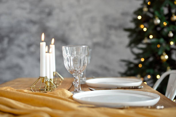 istock Table is served for a Christmas dinner in the living room, close-up view, table setting with a golden tablecloth, white plates, forks, knives, glasses for wine, candles in gold candlesticks, Christmas decorations 1187146942