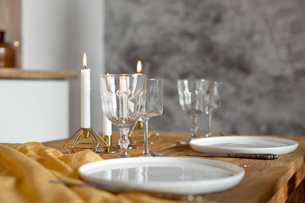istock Table is served for a Christmas dinner in the living room, close-up view, table setting with a golden tablecloth, white plates, forks, knives, glasses for wine, candles in gold candlesticks, Christmas decorations 1187146945
