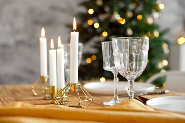 istock Table is served for a Christmas dinner in the living room, close-up view, table setting with a golden tablecloth, white plates, forks, knives, glasses for wine, candles in gold candlesticks, Christmas decorations 1187146947