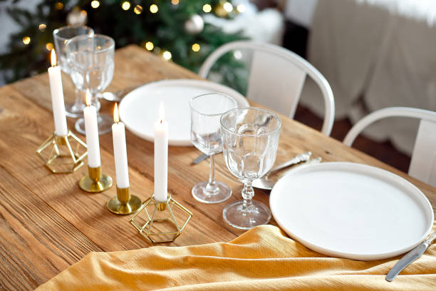 istock Table is served for a Christmas dinner in the living room, close-up view, table setting with a golden tablecloth, white plates, forks, knives, glasses for wine, candles in gold candlesticks, Christmas decorations 1187146951