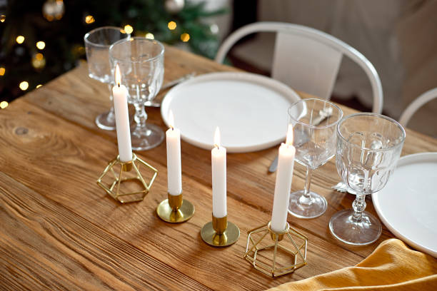 istock Table is served for a Christmas dinner in the living room, close-up view, table setting with a golden tablecloth, white plates, forks, knives, glasses for wine, candles in gold candlesticks, Christmas decorations 1187146954