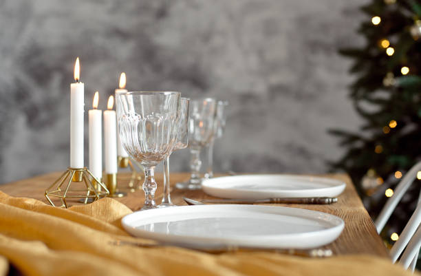 istock Table is served for a Christmas dinner in the living room, close-up view, table setting with a golden tablecloth, white plates, forks, knives, glasses for wine, candles in gold candlesticks, Christmas decorations 1187146957