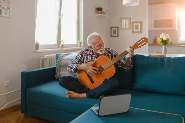 o homem sênior aprende jogar a guitarra em linha da acústica - young at heart audio - fotografias e filmes do acervo