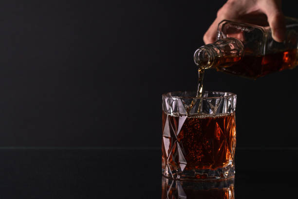 versando whisky dalla bottiglia in vetro - whisky alcohol pouring glass foto e immagini stock