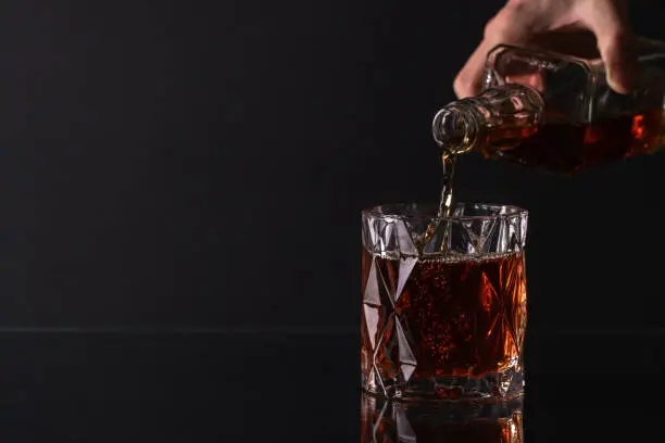 Photo of Pouring whiskey from bottle into glass