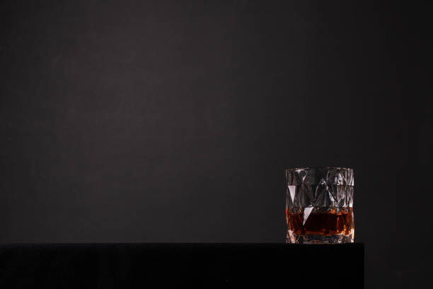 Glass with whiskey on black background