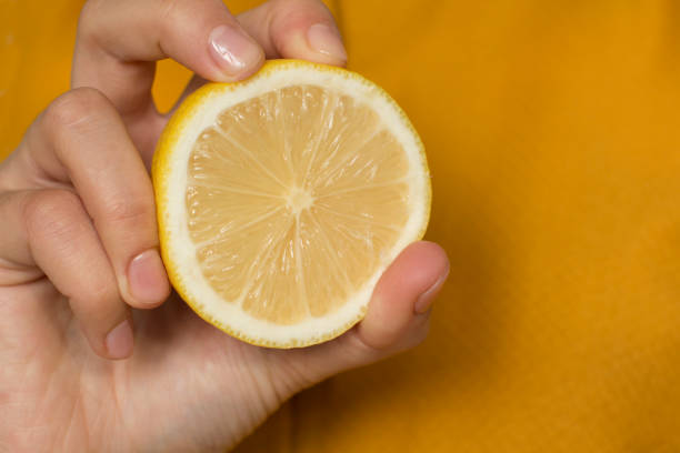 istock young woman in yellow shirt squeezing a lemon 1187153909