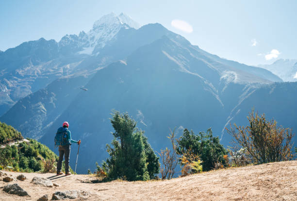 istock Young hiker backpacker man using trekking poles enjoying the Thamserku 6608m mountain with flying rescue helicopter during high altitude Acclimatization walk. Everest Base Camp trekking route, Nepal. 1187155429