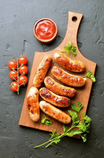 istock Roasted sausages on a cutting board, sause and cherry tomatoes 1187156299