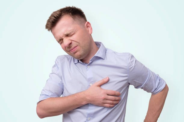 man feeling having heart attack symptom or breast cancer. Caucasian young man feeling suffering and using hand for touching on chest for checking about his heart attack symptom. Breast cancer concept. male chest pain stock pictures, royalty-free photos & images