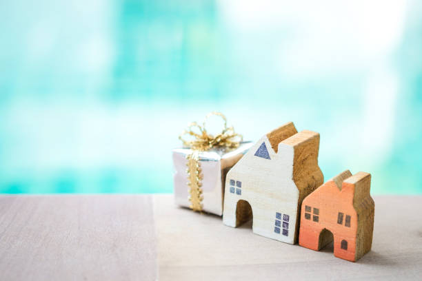 Miniature wooden house with gift box over blurred blue water background