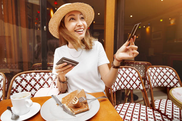 asian girl finished breakfast in a paris retro cafe and pays for lunch by credit card. finance retail transaction and small business concept - food currency breakfast business imagens e fotografias de stock
