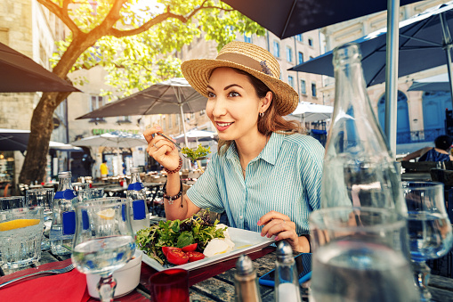Happy asian woman eating healthy meal in outdoor restaurant