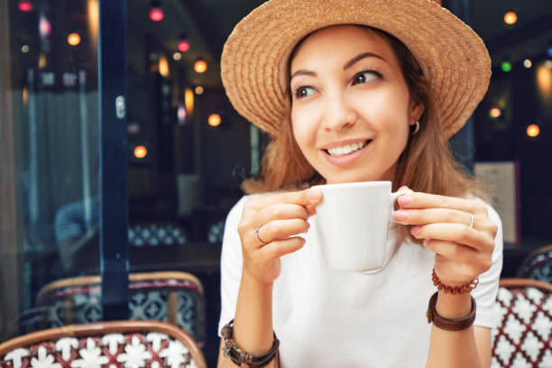 Portrait of young Asian woman drinking coffee in a cafe. Focus on white cup Portrait of young Asian woman drinking coffee in a cafe. Focus on white cup hot filipina women stock pictures, royalty-free photos & images