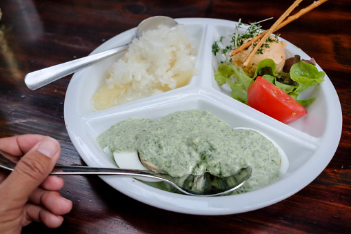 Close up Asian woman eating Frankfurt specialties food: cheeses marinated in oil, vinegar and chopped onions, green sauce with eggs, and Sachsenhausen cream cheese